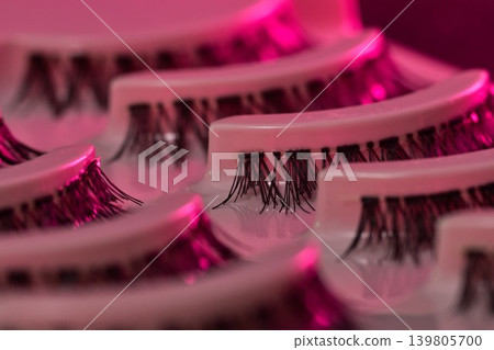 Lash display scene. Eyelash trays under vibrant neon illumination. Luxurious lash presentation using colorful ambient lighting effects Lash display scene. Eyelash trays under vibrant neon illumination. Luxurious lash presentation using colorful ambient lighting effects 139805700