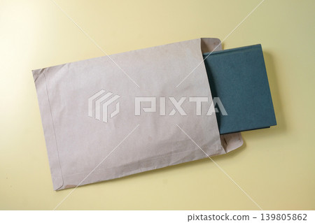Hard cover book in document envelope on background. Hard cover book in document envelope on background. 139805862
