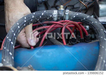 Mechanic diagnosing car engine ignition wires Mechanic diagnosing car engine ignition wires 139806152