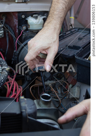 Mechanic checking engine fluid level in a vehicle Mechanic checking engine fluid level in a vehicle 139806153