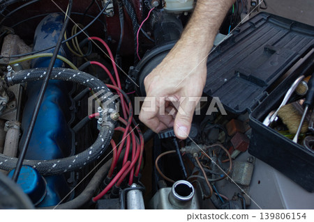 Mechanic checking engine fluid level in a car Mechanic checking engine fluid level in a car 139806154