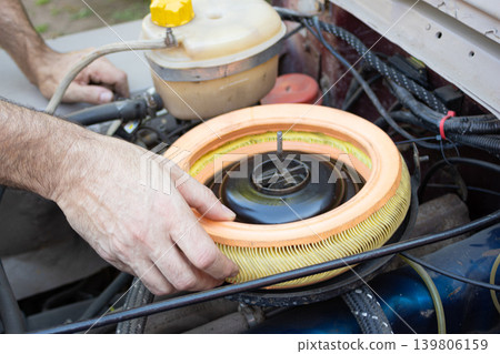 Mechanic changing air filter in an old car engine Mechanic changing air filter in an old car engine 139806159