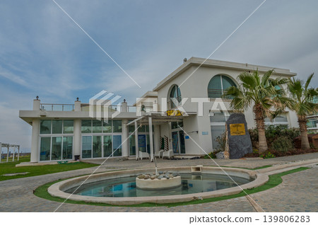 Modern architectural gem on the coast surrounded by palm trees and serene water features Modern architectural gem on the coast surrounded by palm trees and serene water features 139806283