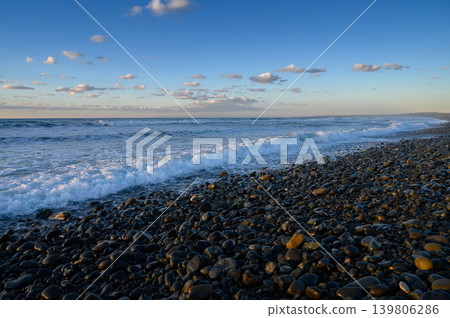 Stunning coastal view with rolling waves and pebbles at golden hour Stunning coastal view with rolling waves and pebbles at golden hour 139806286