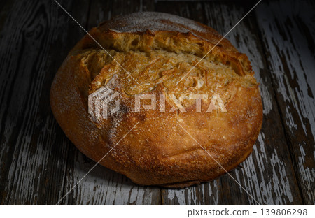 Freshly baked artisanal bread resting on a rustic wooden surface in a cozy Freshly baked artisanal bread resting on a rustic wooden surface in a cozy 139806298