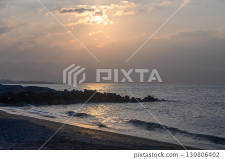 Golden sunset washes over tranquil shoreline as waves softly lap on sandy beach Golden sunset washes over tranquil shoreline as waves softly lap on sandy beach 139806402
