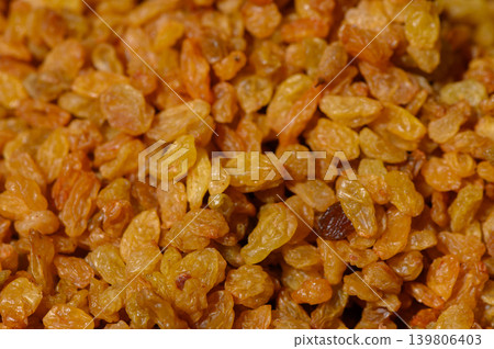 Golden raisins glistening in sunlight, showcasing natural sweetness and vibrant color in a rustic kitchen setting 139806403