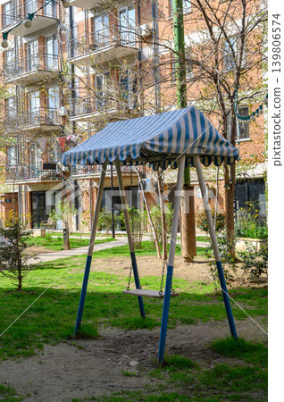 Swing set with blue-and-white striped canopy on playground Swing set with blue-and-white striped canopy on playground 139806574