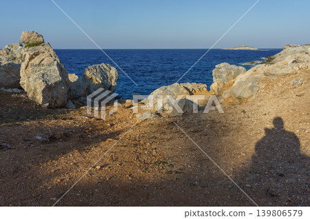 Serene coastal path leading to the tranquil blue ocean under a clear sky at sunset. Serene coastal path leading to the tranquil blue ocean under a clear sky at sunset. 139806579