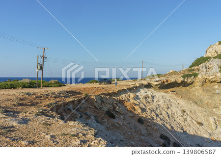 A serene coastal view at dusk with distant cliffs and a lone figure enjoying the tranquil shoreline. A serene coastal view at dusk with distant cliffs and a lone figure enjoying the tranquil shoreline. 139806587