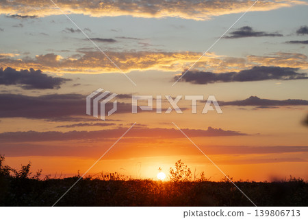 Horizon view across a vast agricultural field at sunset with an expressive sky full of colorful clouds, representing sustainable farming and the beauty of rural argentina Horizon view across a vast agricultural field at sunset with an expressive sky full of colorful clouds, representing sustainable farming and the beauty of rural argentina 139806713