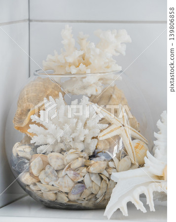 Glass bowl filled with seashells, starfish, and white coral. Coastal home decoration and beach themed abstract art for interior design. Glass bowl filled with seashells, starfish, and white coral. Coastal home decoration and beach themed abstract art for interior design. 139806858