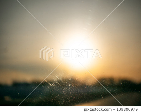 Bright sun shining through a dirty windshield at sunrise. Golden hour light and abstract dirty glass for background texture. Bright sun shining through a dirty windshield at sunrise. Golden hour light and abstract dirty glass for background texture. 139806979