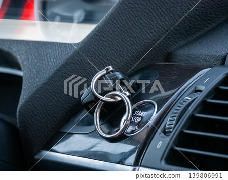Car remote starter key fob attached to push button start stop engine button. Modern vehicle ignition system and comfort of smart key. Car remote starter key fob attached to push button start stop engine button. Modern vehicle ignition system and comfort of smart key. 139806991
