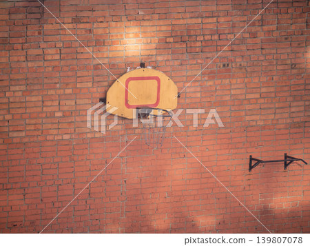 Old basketball hoop on brick wall with pull up bar. Urban sport equipment for street fitness and game. Outdoor activity concept. Old basketball hoop on brick wall with pull up bar. Urban sport equipment for street fitness and game. Outdoor activity concept. 139807078