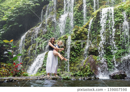 Happy mother and daughter hugging near waterfall in Bali 139807598