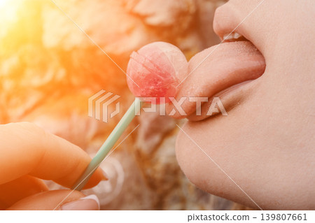 Lollipop tongue candy Close up of a person licking a pink round lollipop during a warm and bright sunny day Lollipop tongue candy Close up of a person licking a pink round lollipop during a warm and bright sunny day 139807661