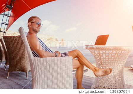 Entrepreneur remote seaside man relaxing at outdoor cafe terrace with laptop during summer sunset vacation Entrepreneur remote seaside man relaxing at outdoor cafe terrace with laptop during summer sunset vacation 139807664