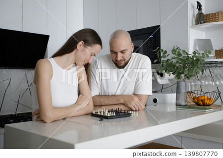 Smiling woman and man playing chess at home Smiling woman and man playing chess at home 139807770