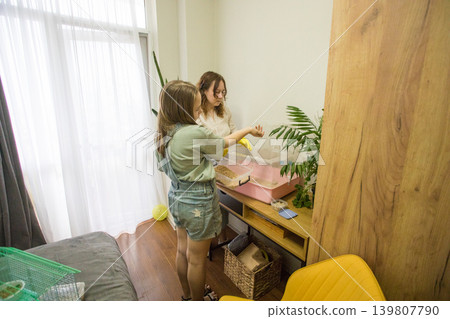 Two individuals stand in a room arranging small animal cages. Two individuals stand in a room arranging small animal cages. 139807790
