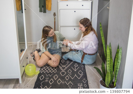 Two friends sit on a rug in a hallway playing with a pet and enjoying their time Two friends sit on a rug in a hallway playing with a pet and enjoying their time 139807794