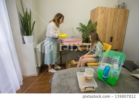 Mom and daughter are working together to set up a pet enclosure in a bedroom. Mom and daughter are working together to set up a pet enclosure in a bedroom. 139807812