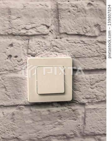 Modern white light switch on textured white painted brick wall vertical Modern white light switch on textured white painted brick wall vertical 139807834