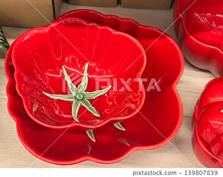 Red ceramic tomato shaped bowls and plate stacked on wooden surface Red ceramic tomato shaped bowls and plate stacked on wooden surface 139807839