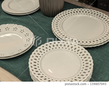 White ceramic plates with lace cutout border on green table runner White ceramic plates with lace cutout border on green table runner 139807843
