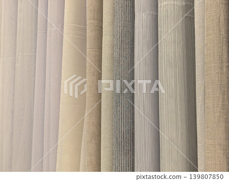 Sheer curtain fabric samples in neutral tones hanging in showroom display Sheer curtain fabric samples in neutral tones hanging in showroom display 139807850