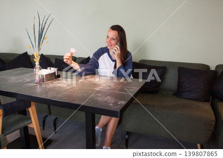 Joyful woman talking on the phone in cafe. Beautiful woman with long dark healthy hair. Female 40s Joyful woman talking on the phone in cafe. Beautiful woman with long dark healthy hair. Female 40s 139807865