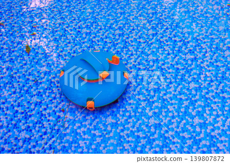 Vacuum robot cleaner works on surface of clear blue swimming pool while sunlight shines overhead. Vacuum robot cleaner works on surface of clear blue swimming pool while sunlight shines overhead. 139807872