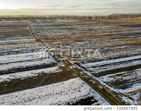 Top view of empty snowy fields patched landscape, dark horizon and bright sky on sunny winter day. Aerial drone photography concept. 139807895