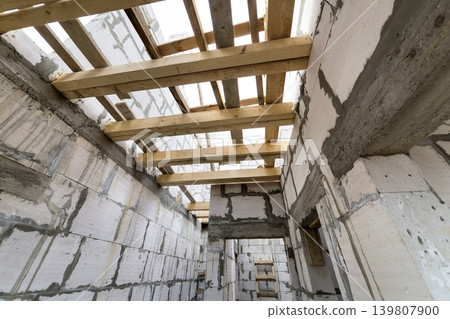 House room interior under construction and renovation. Energy saving walls of hollow foam insulation blocks, wooden ceiling beams and roof frame. 139807900