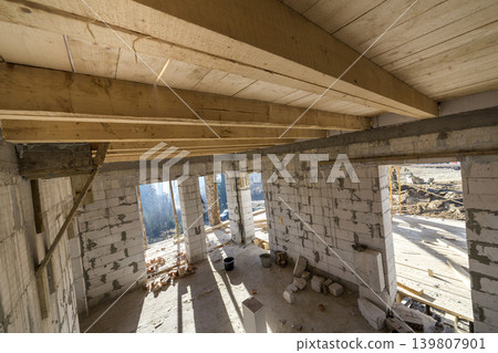 House room interior under construction and renovation. Energy saving walls of hollow foam insulation blocks, wooden ceiling beams and roof frame. House room interior under construction and renovation. Energy saving walls of hollow foam insulation blocks, wooden ceiling beams and roof frame. 139807901