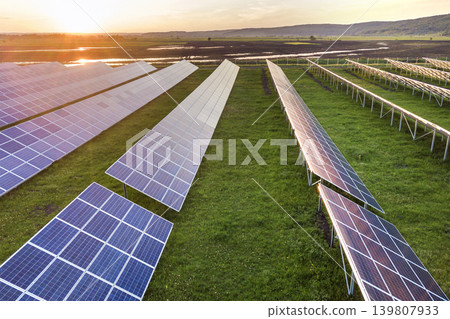 Blue solar photo voltaic panels system producing renewable clean energy on rural landscape and setting sun background. 139807933