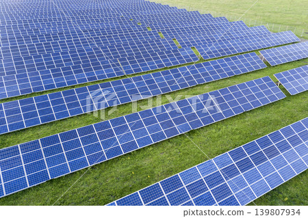 Large field of solar photo voltaic panels system producing renewable clean energy on green grass background. Large field of solar photo voltaic panels system producing renewable clean energy on green grass background. 139807934
