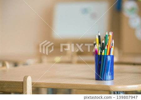 Wooden colorful drawing pencils arranged in plastic jug on light copy space background. Wooden colorful drawing pencils arranged in plastic jug on light copy space background. 139807947