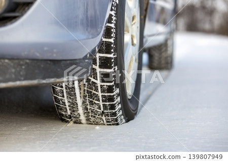 Close up of a car tire parked on snowy road on winter day. Transportation and safety concept. Close up of a car tire parked on snowy road on winter day. Transportation and safety concept. 139807949