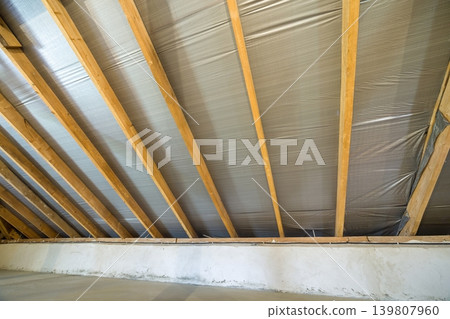 Attic of a building with wooden beams of a roof structure. Attic of a building with wooden beams of a roof structure. 139807960