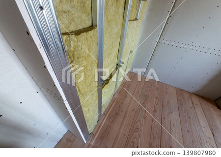 Wall of a room under renovation with mineral rock wool insulation and metal frame prepared for drywall plates. Wall of a room under renovation with mineral rock wool insulation and metal frame prepared for drywall plates. 139807980