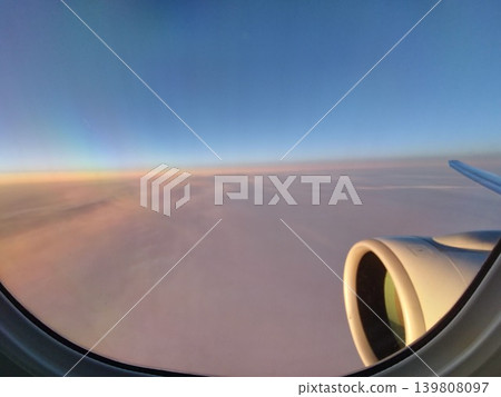 Passenger airplane window view above clouds during morning flight Passenger airplane window view above clouds during morning flight 139808097