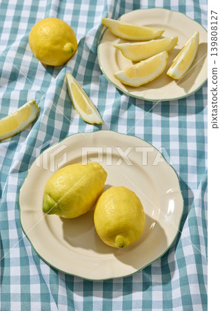 Fresh Lemons on a White Ceramic Plate on a Blue Plaid Tablecloth. Top View Fresh Lemons on a White Ceramic Plate on a Blue Plaid Tablecloth. Top View 139808127