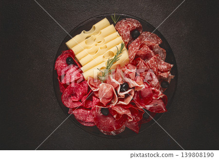 Cold cuts, appetizer, prosciutto, salami and ham, with maasdam cheese and olives, on a round plate, breakfast, top view, close-up, deserted 139808190