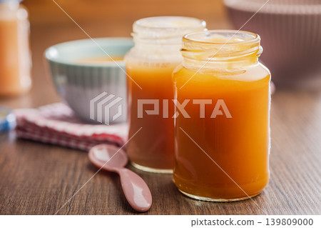 Creamy Carrot Baby Food Puree in Glass Jars With Bowl and Spoon on Wooden Table 139809000