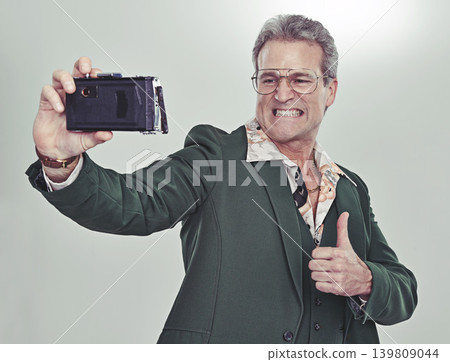 Senior man, fashion and selfie with thumbs up for good job, winning or photography on a gray studio background. Mature person in retro or vintage style and like emoji or yes sign for photo or picture 139809044