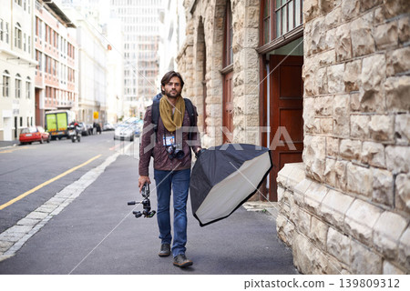 Camera, equipment and photographer in city for photoshoot with lighting gear on street. Cameraman, walking and professional photography tools for press, project and person travel with technology Camera, equipment and photographer in city for photoshoot with lighting gear on street. Cameraman, walking and professional photography tools for press, project and person travel with technology 139809312
