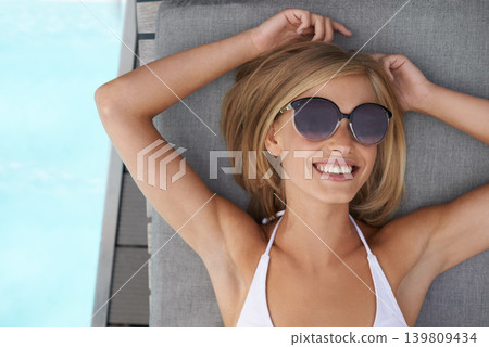 Woman, bikini and sun bathing at pool with sunglasses for holiday swimming, outdoor or vacation. Female person, relax and smile on patio furniture with shades for summer rest, stress relief or Miami Woman, bikini and sun bathing at pool with sunglasses for holiday swimming, outdoor or vacation. Female person, relax and smile on patio furniture with shades for summer rest, stress relief or Miami 139809434