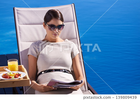 Woman, reading and magazine on sunbed outdoor with sunglasses for relax, snacks and lifestyle news. Person, publication and paper by pool on holiday, vacation and summer trip at hotel or mockup space Woman, reading and magazine on sunbed outdoor with sunglasses for relax, snacks and lifestyle news. Person, publication and paper by pool on holiday, vacation and summer trip at hotel or mockup space 139809439