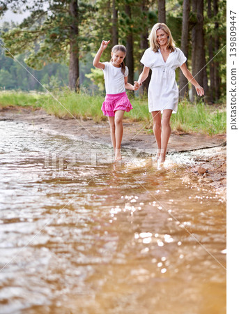 Mother, daughter and happiness outdoor in river for bonding, support or holding hands on holiday in nature. Family, woman and girl child with smile or adventure on vacation, travel and lake with love Mother, daughter and happiness outdoor in river for bonding, support or holding hands on holiday in nature. Family, woman and girl child with smile or adventure on vacation, travel and lake with love 139809447